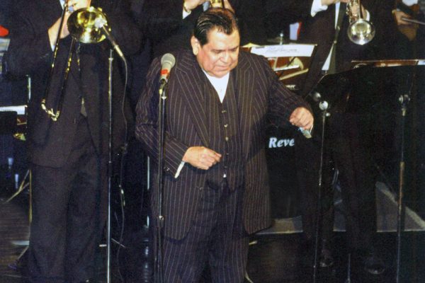 Front of band Latin music icon, singer Vitín Avilés, left to right: Mike Molina - bongo bell, Demetrios Kastaris - trombone, Jose Mercado - trumpet, Steve Gluzband - trumpet, right corner: Alí Bello - violin, The Point CDC in the Bronx, New York, February 4, 2000. Tribute concert to Vitín Avilés.