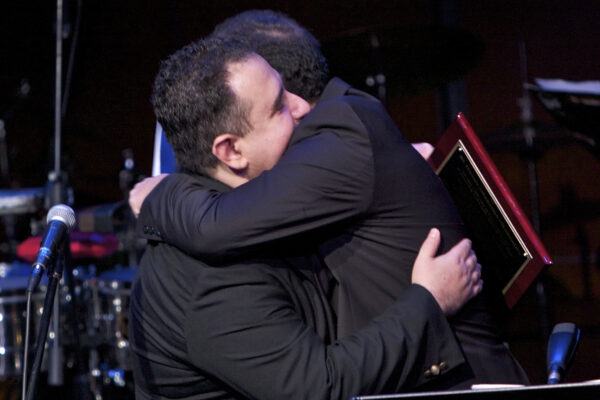 An emotional moment after Demetrios gives Yanni a beautiful plaque to take back to Greece with him after his performance with the Latin Jazz Coalition at Flushing Town Hall, Queens New York, December 10, 2010. Photo credit: Norm Harris.